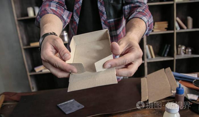 年輕男子皮革制造商手動組裝產(chǎn)品的紙板包裝盒子
